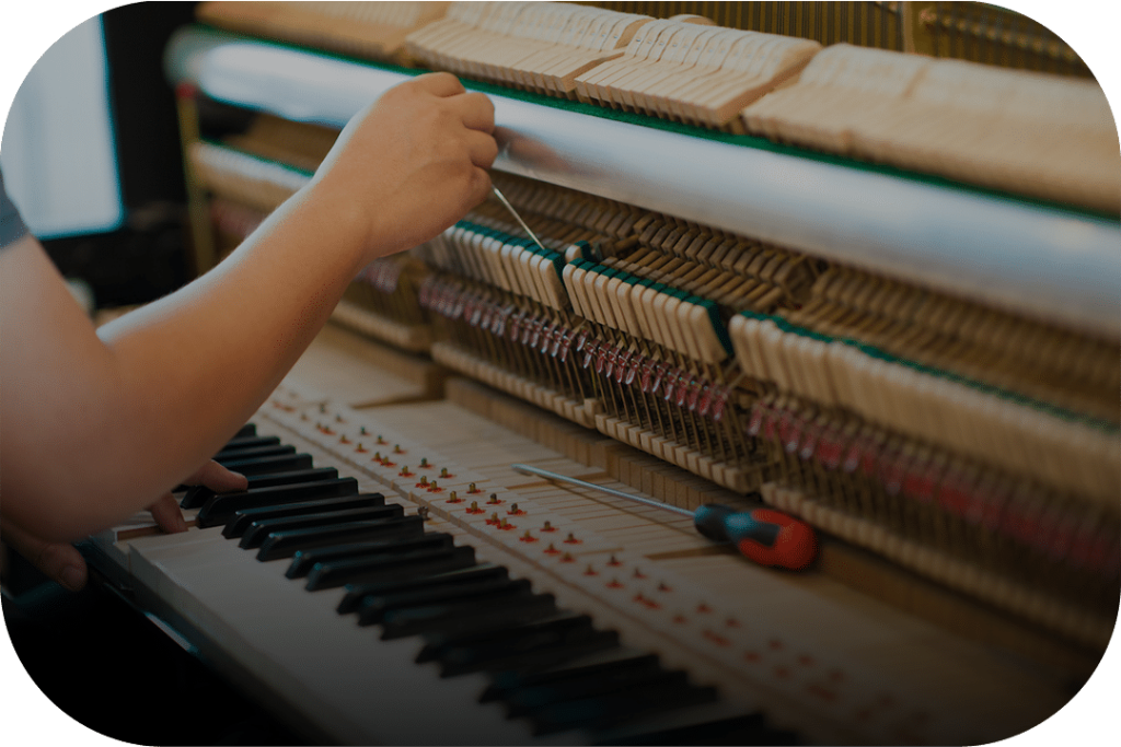 Piano technician tuning an upright piano
